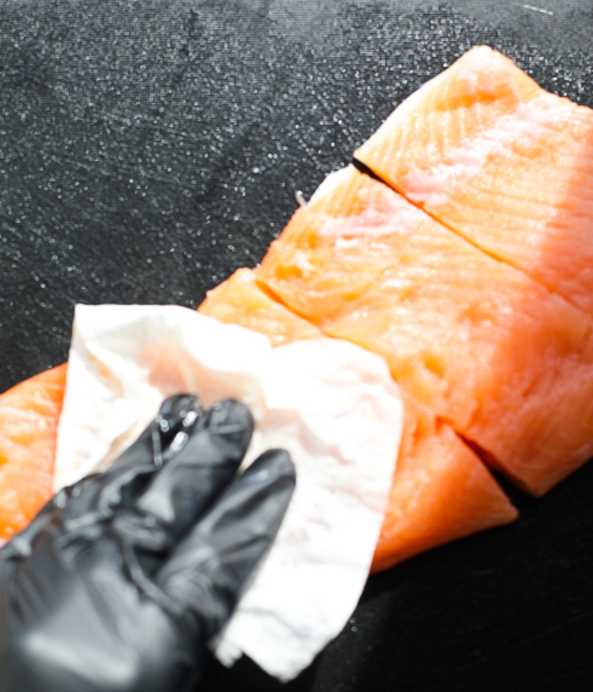 Uncooked salmon pat dru with a paper towel.