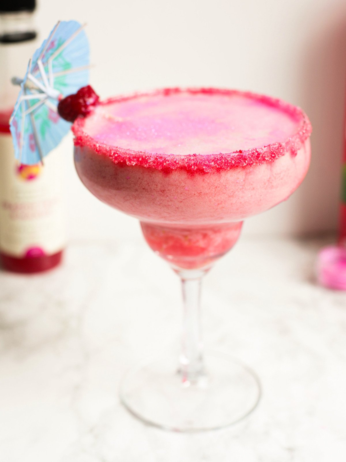 barbie pina colada in a cocktail glass with a blue umbrella.