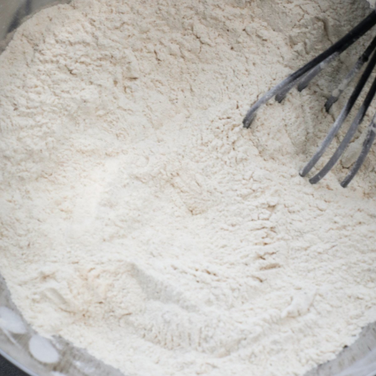 Flour, cinnamon and nutmeg stirred in a silver bowl.