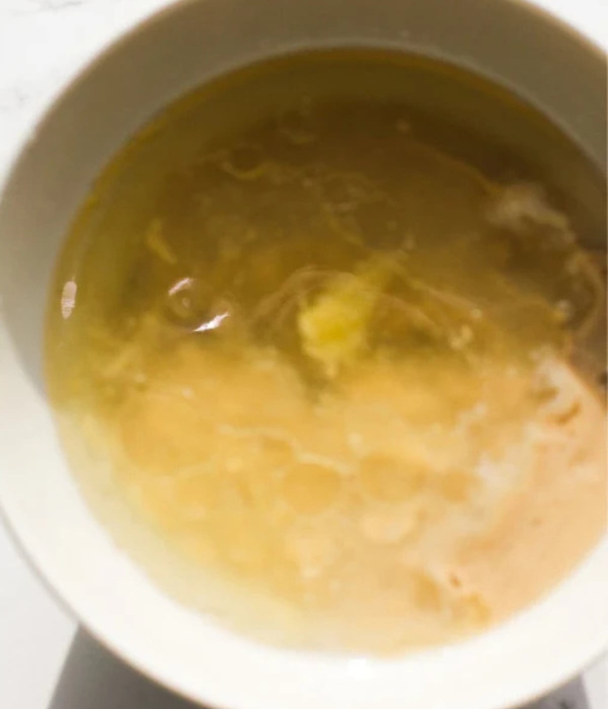 Tahini, oil and water in a white bowl.