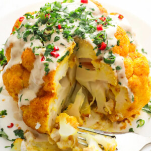 Turmeric cauliflower with tahini dressing, herbs and chili on top.