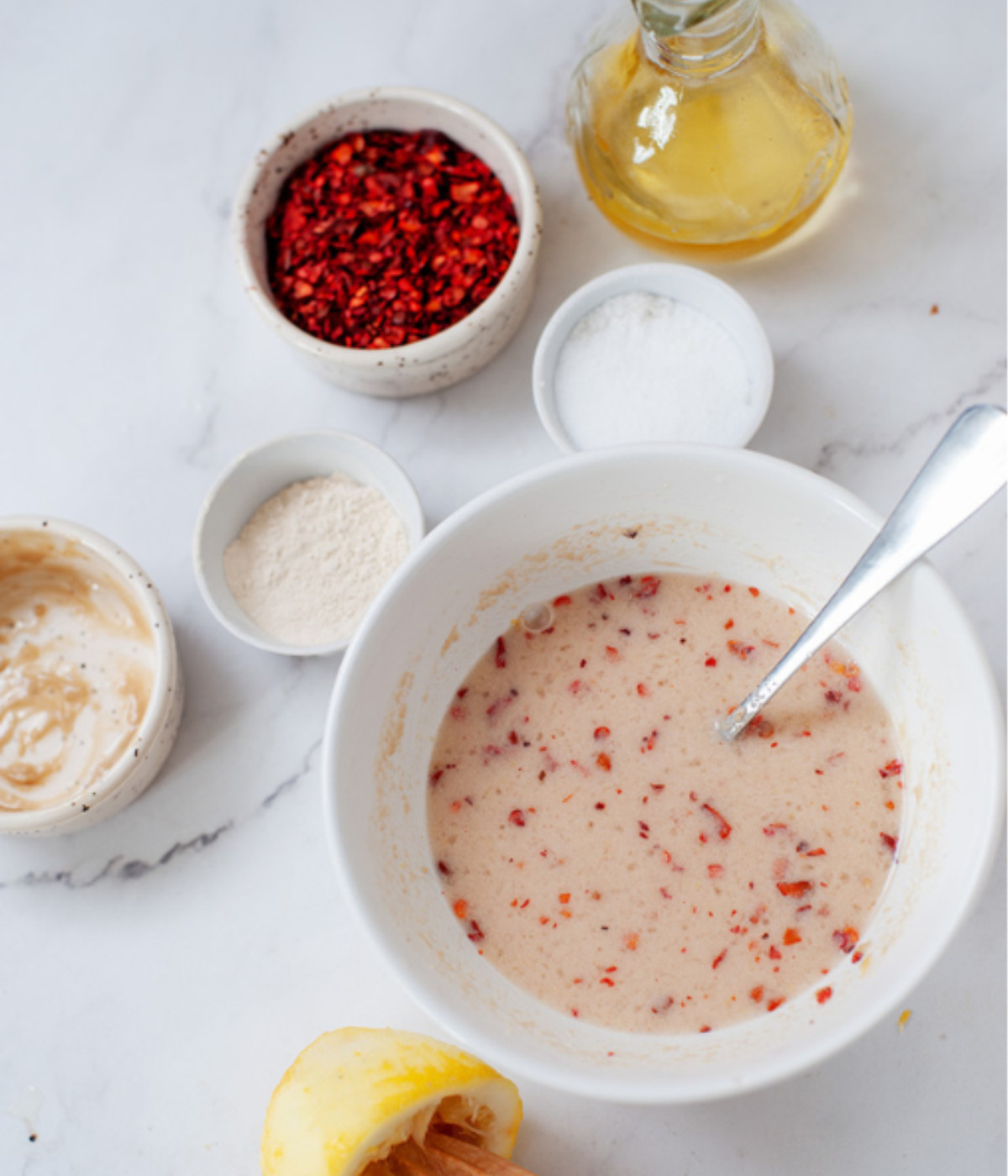 Chilli flakes, lemon juice, zest, tahini and salt mixed in a white bowl.
