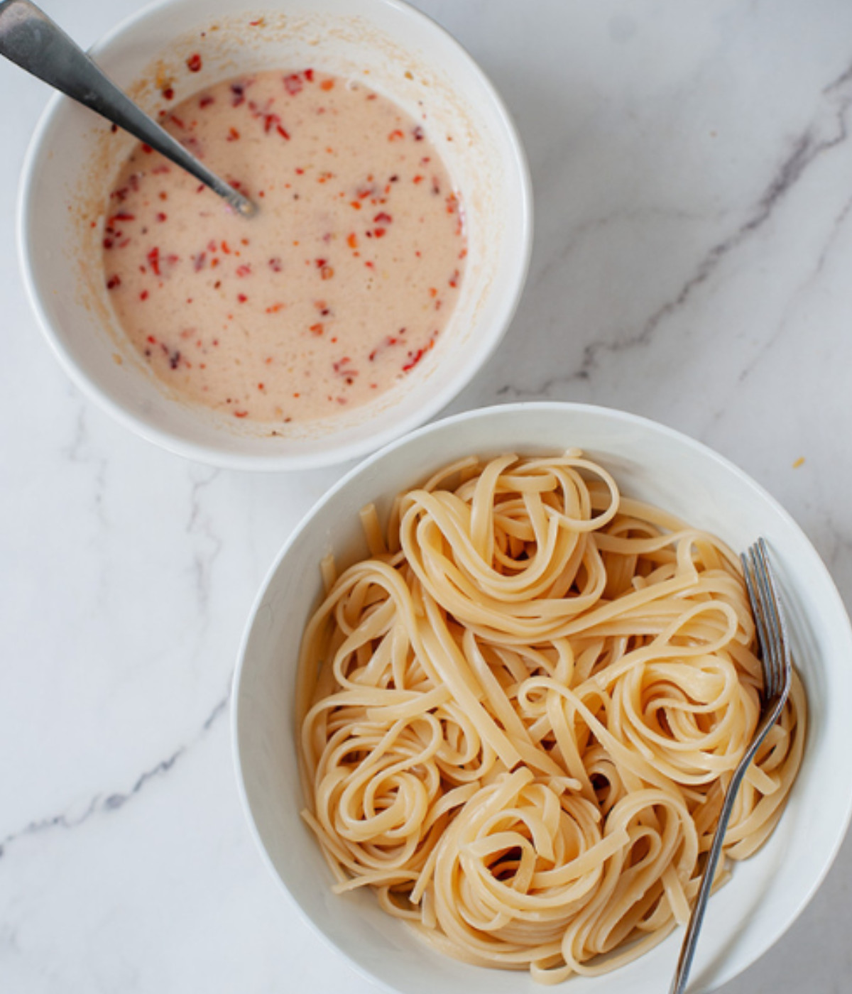 Pasta in a white bowl and tahini sauce in a small bowl.