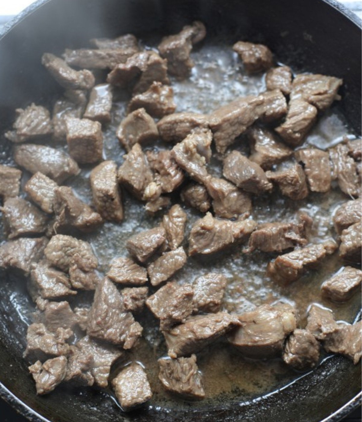 Chopped beef cooking in a black pan.