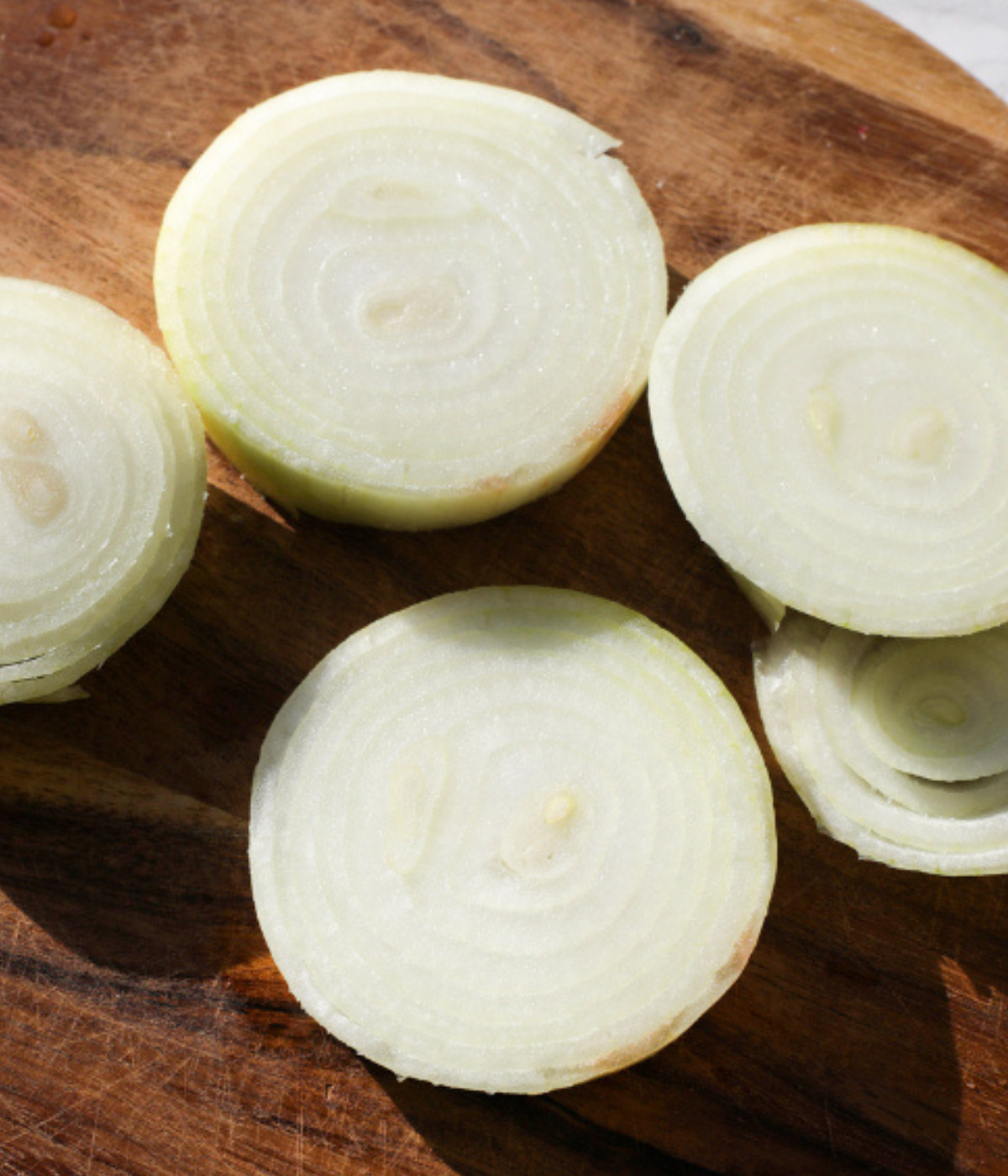 Large onions chopped on a brown chopping board.