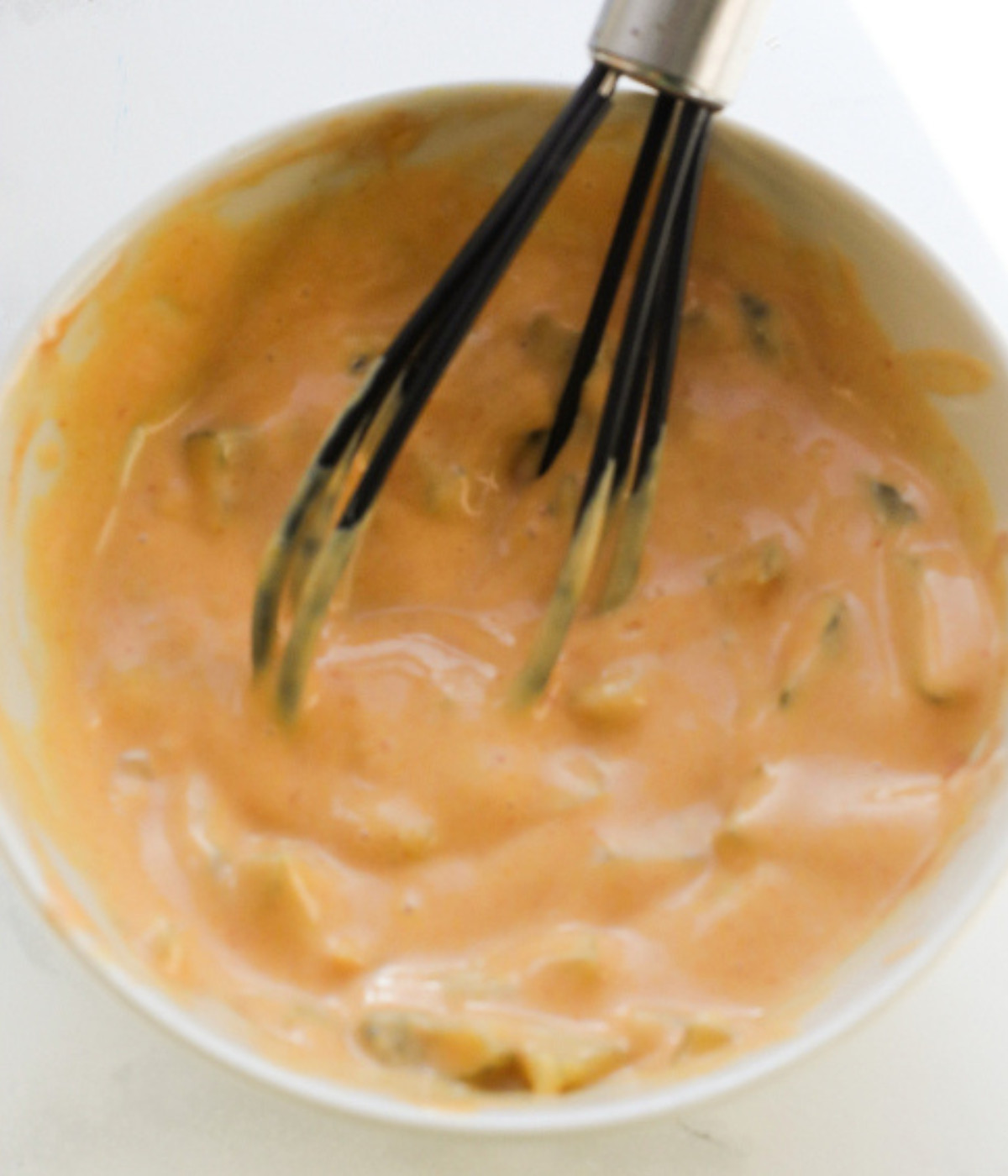 Whisked mustard, ketchup, mayonnaise and gherkins in a bowl.