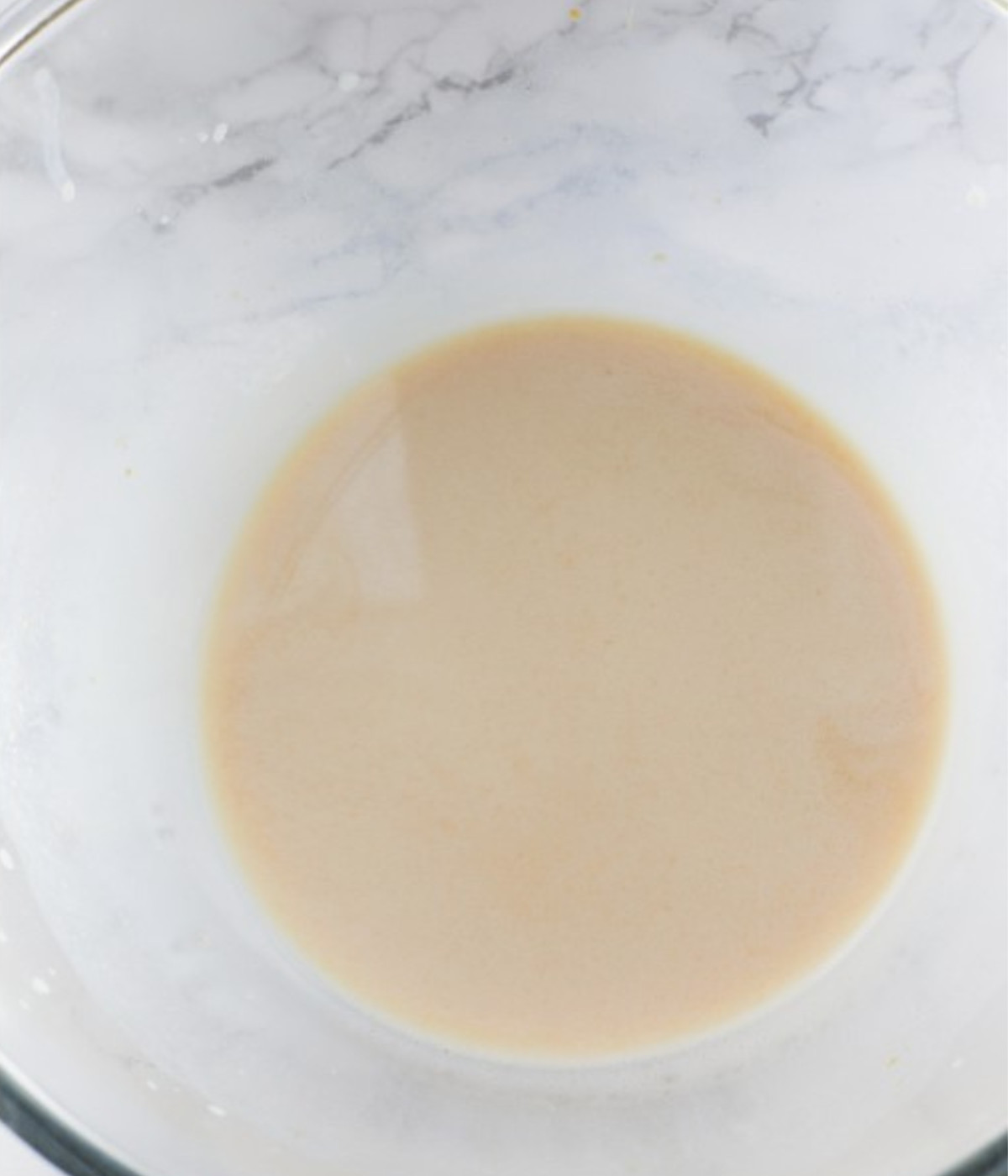 Milk and lotus biscoff spread mixed in a glass bowl.