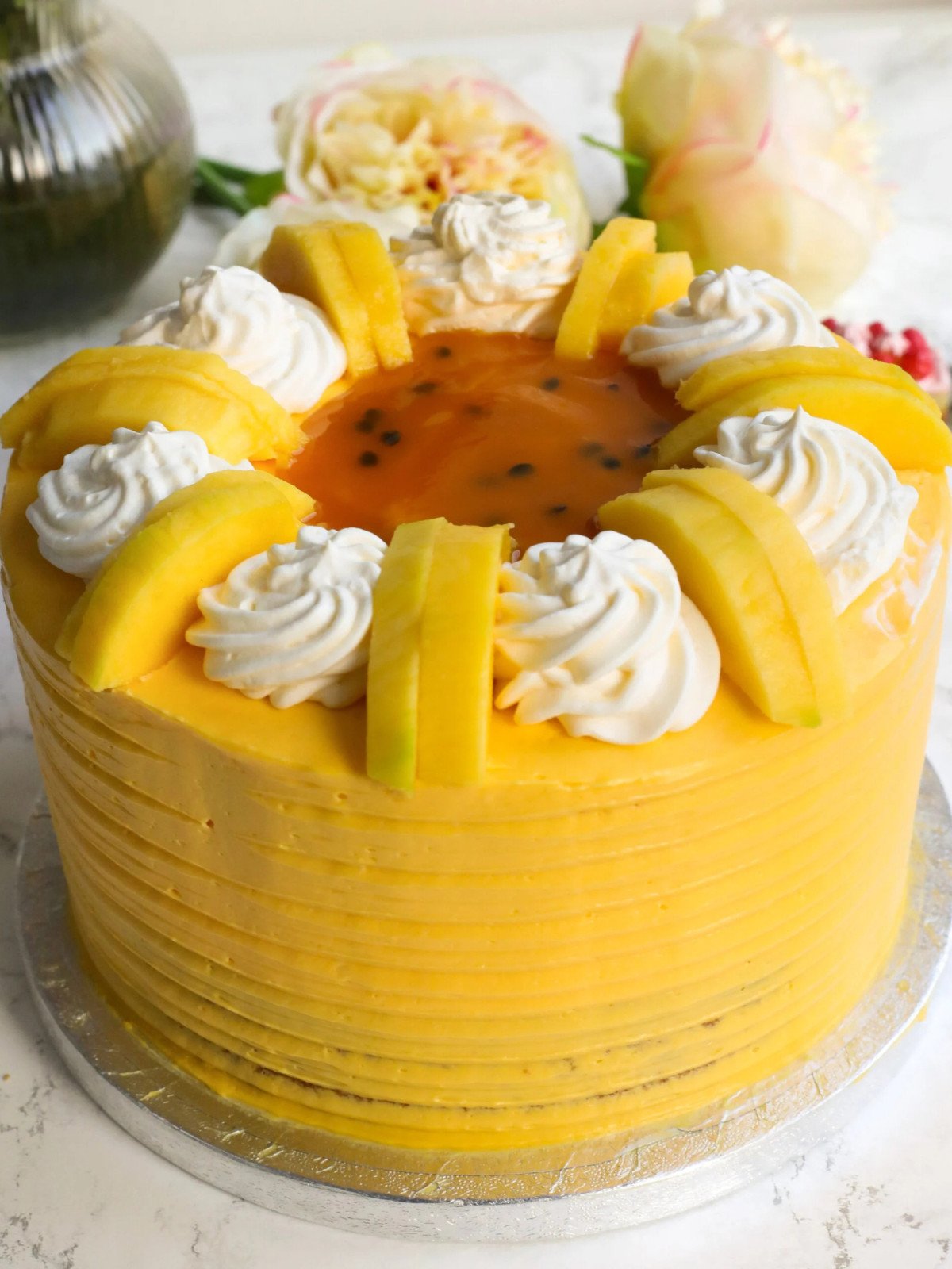 Mangoes and passionfruit cake on a cake board.