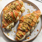 Pistachio croissant on a grey plate.