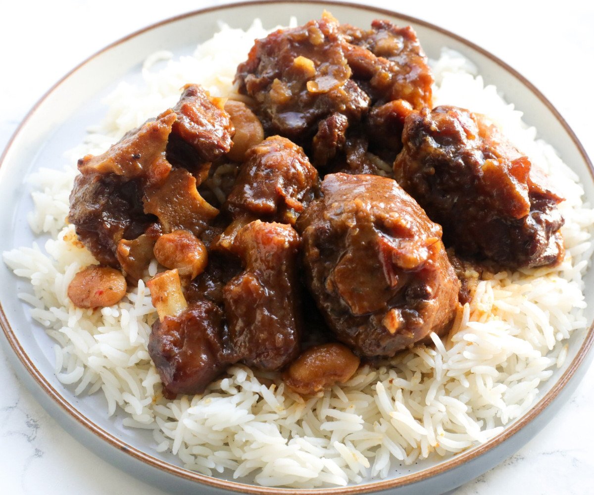 Caribbean oxtail served with white rice in a plate.