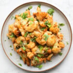 air-fried cauliflower on a grey plate with a gold rim, topped with parsley and parmesan.