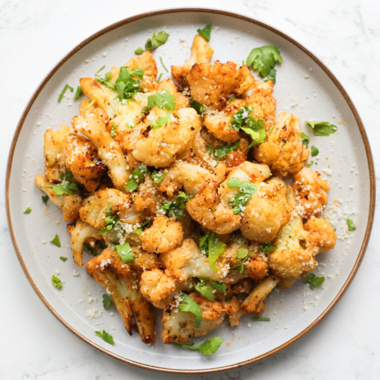 air-fried cauliflower on a grey plate with a gold rim, topped with parsley and parmesan.