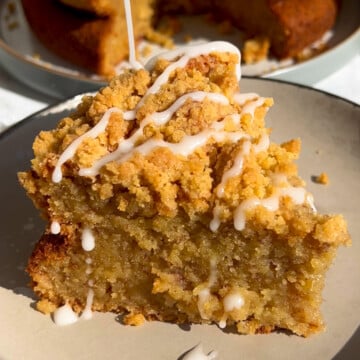 A slice of banana cake with crumble and icing on top.
