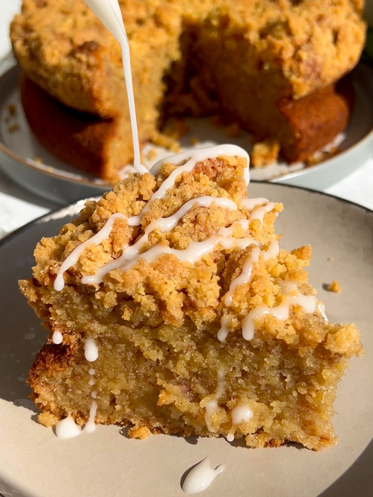 Banana cake slice with streussel and icing on top.
