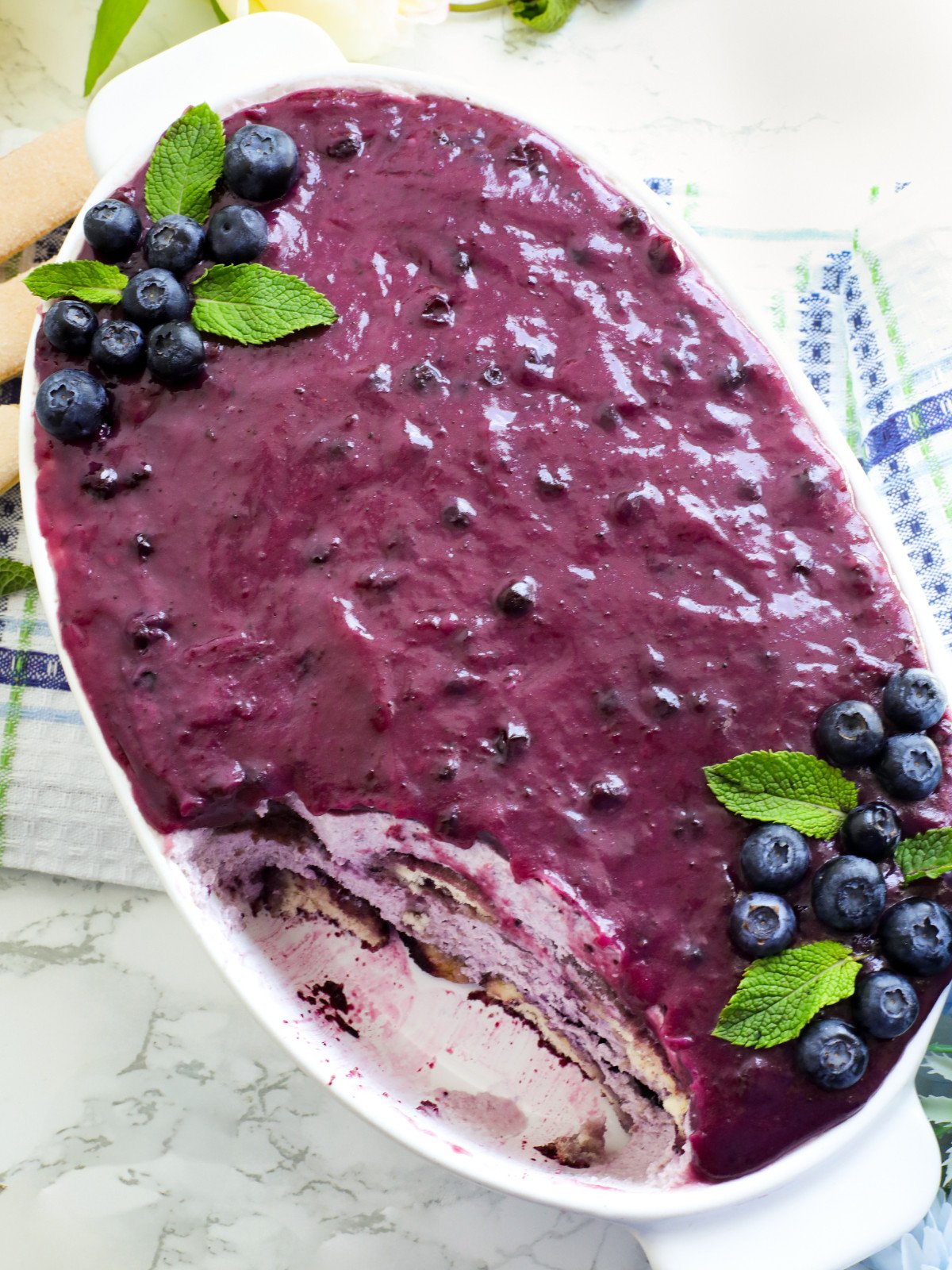 Blue berry tiramisu in a white oval dish on a table.