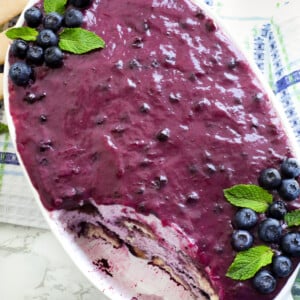 Blue berry tiramisu in a white oval dish topped with blueberries and mint leaves.
