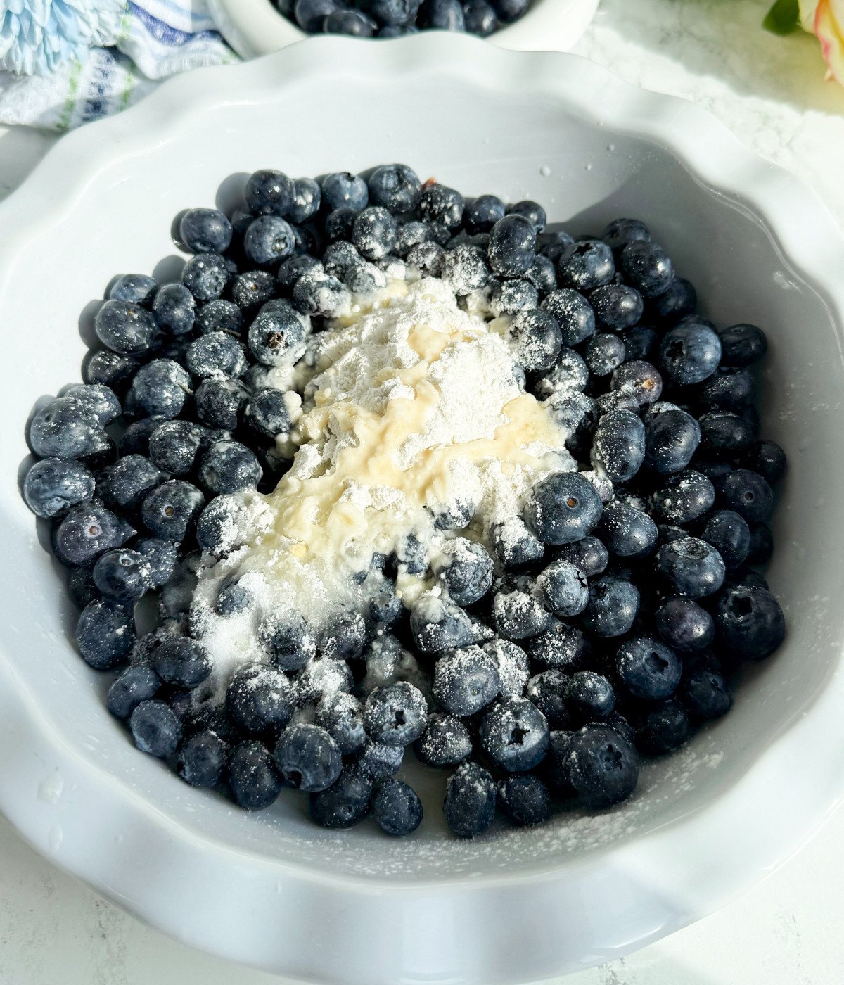 Blueberries, lemon, flour in a white pie dish.