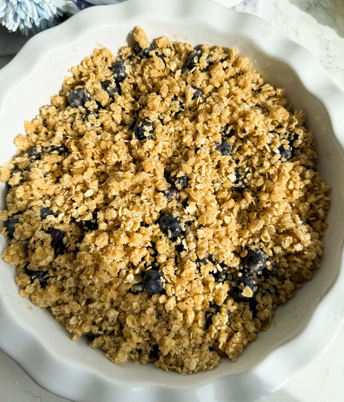 Blueberries with oat crisp on top in a white pie dish.