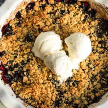Blueberry crisp with three scoops of ice cream on top.