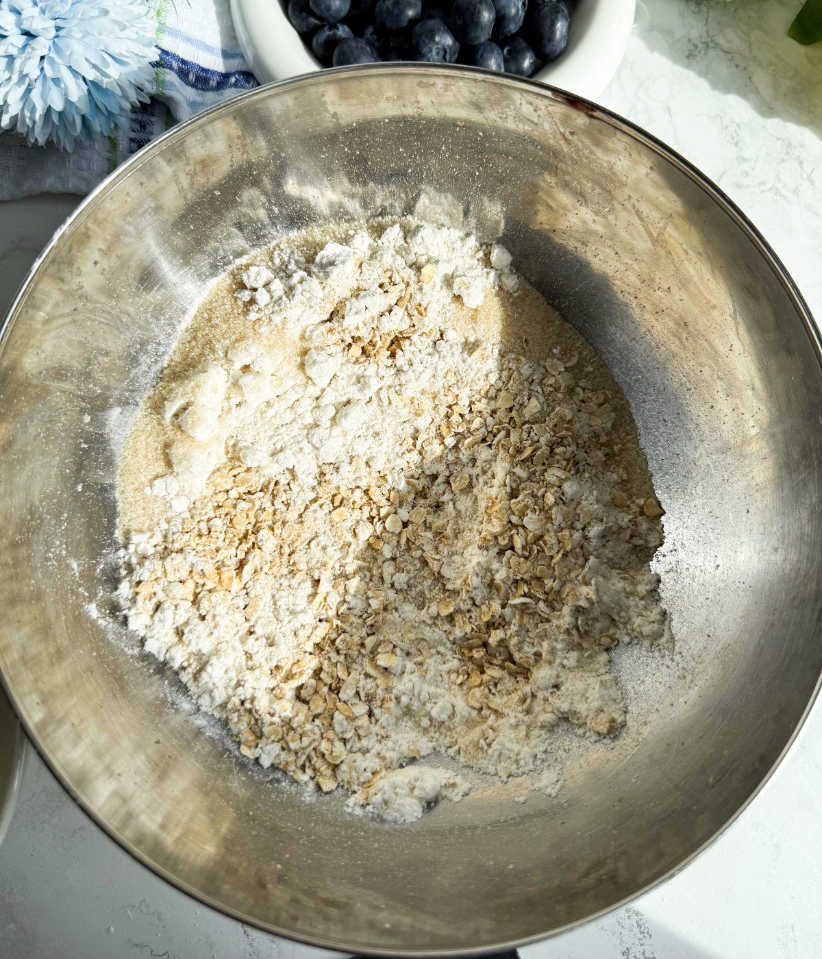 Brown sugar, flour, oats and cinnamon in a silver bowl.