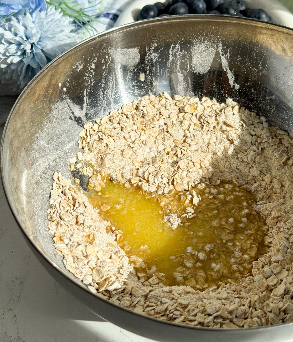 Brown sugar, flour, oats, melted butter and cinnamon in a silver bowl.