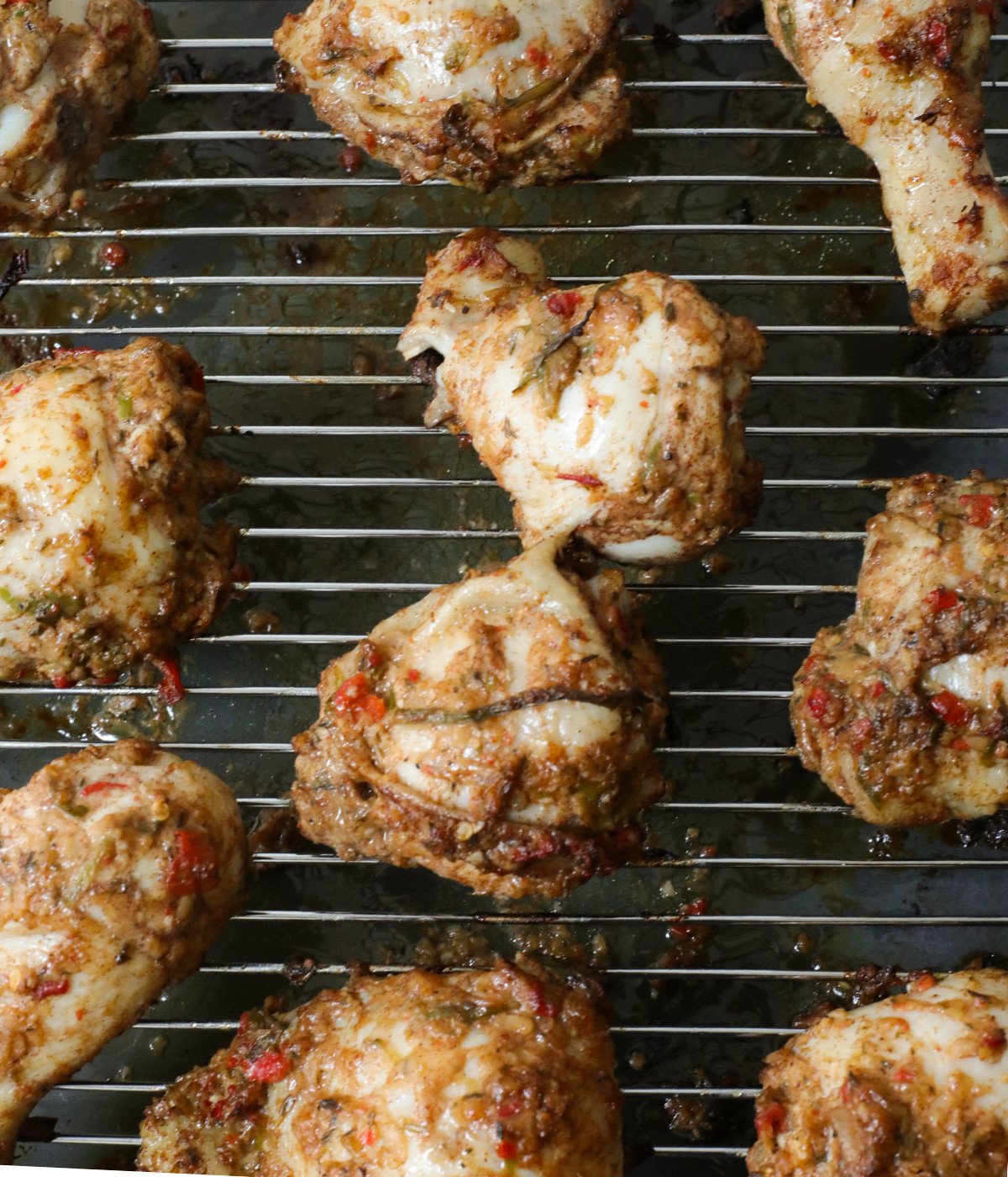 Grilled thighs, drums and jerk marinade on an oven rack.