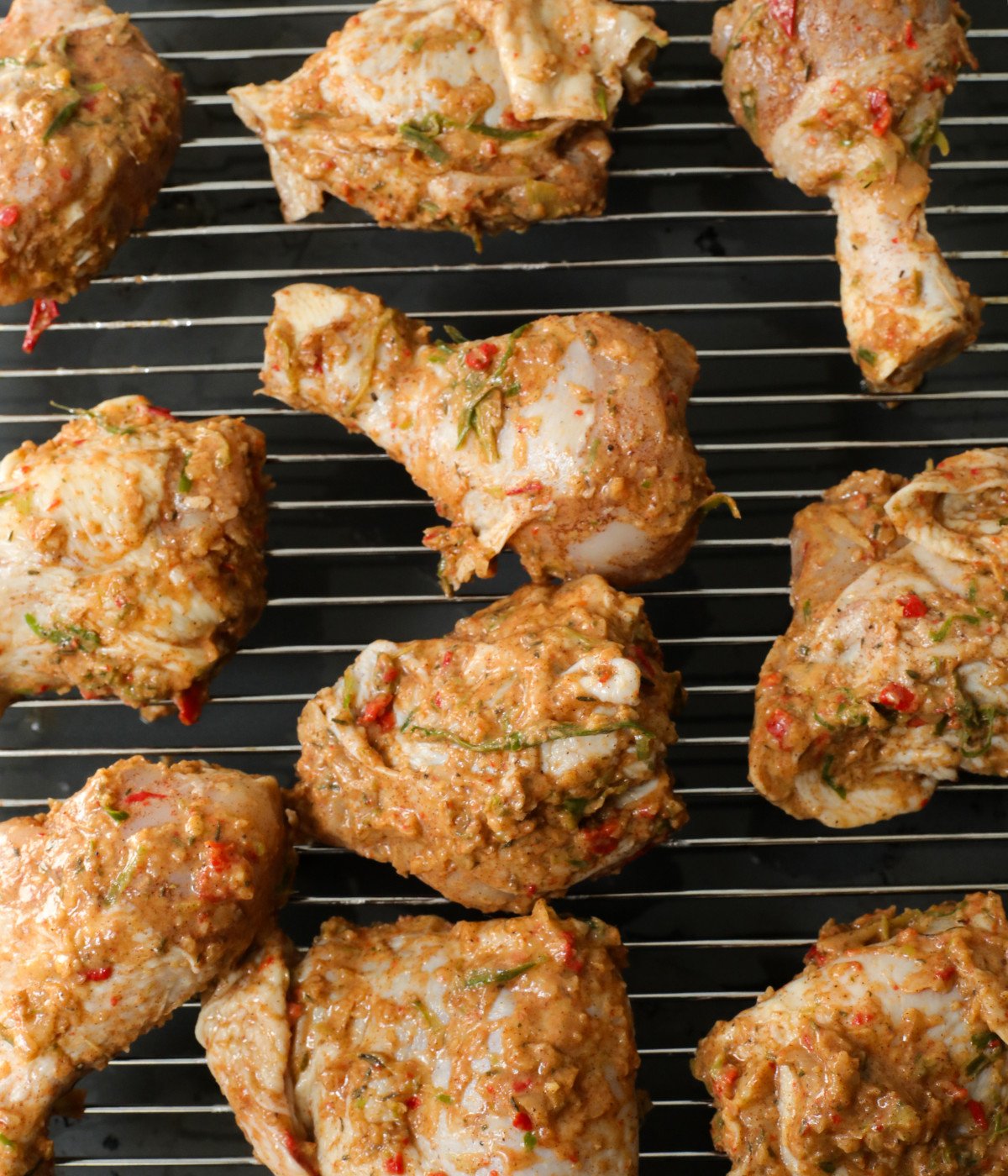 Thighs, drums and jerk marinade on an oven rack.