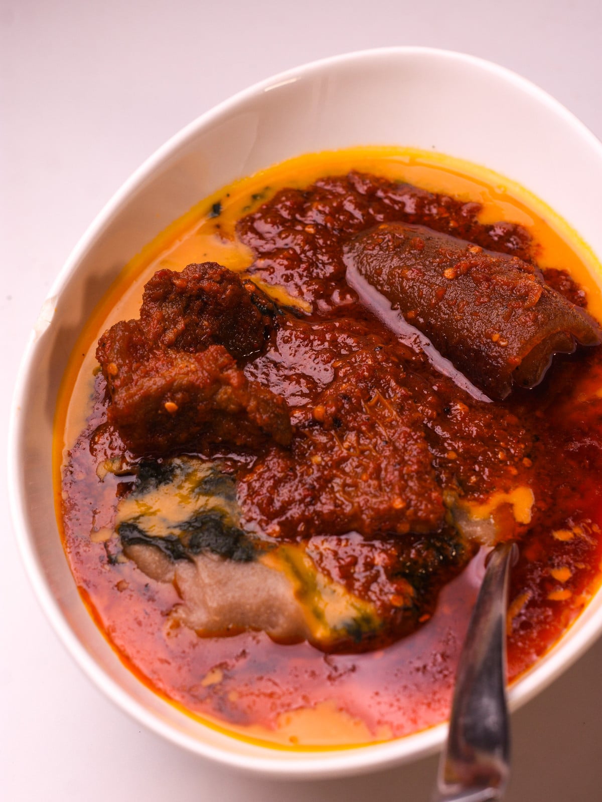 Amala, ewedu, gbegiri and obe ata in a white oval bowl.
