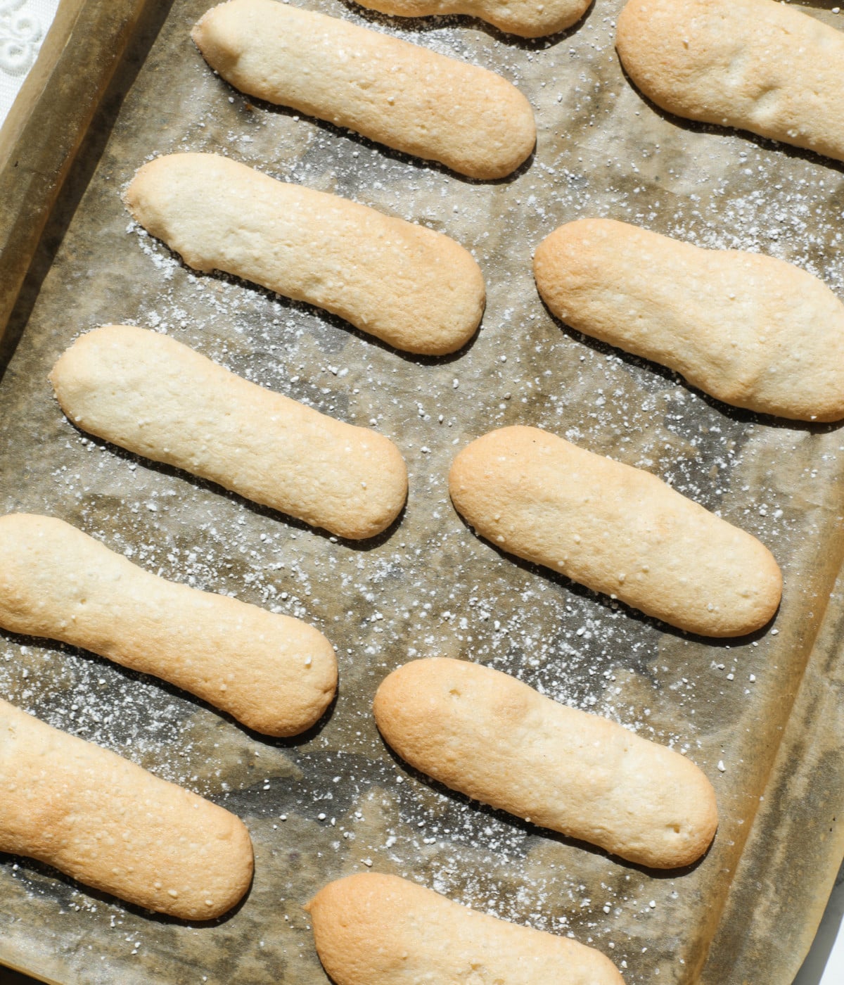 Ladyfingers baked on a lined baking sheet.