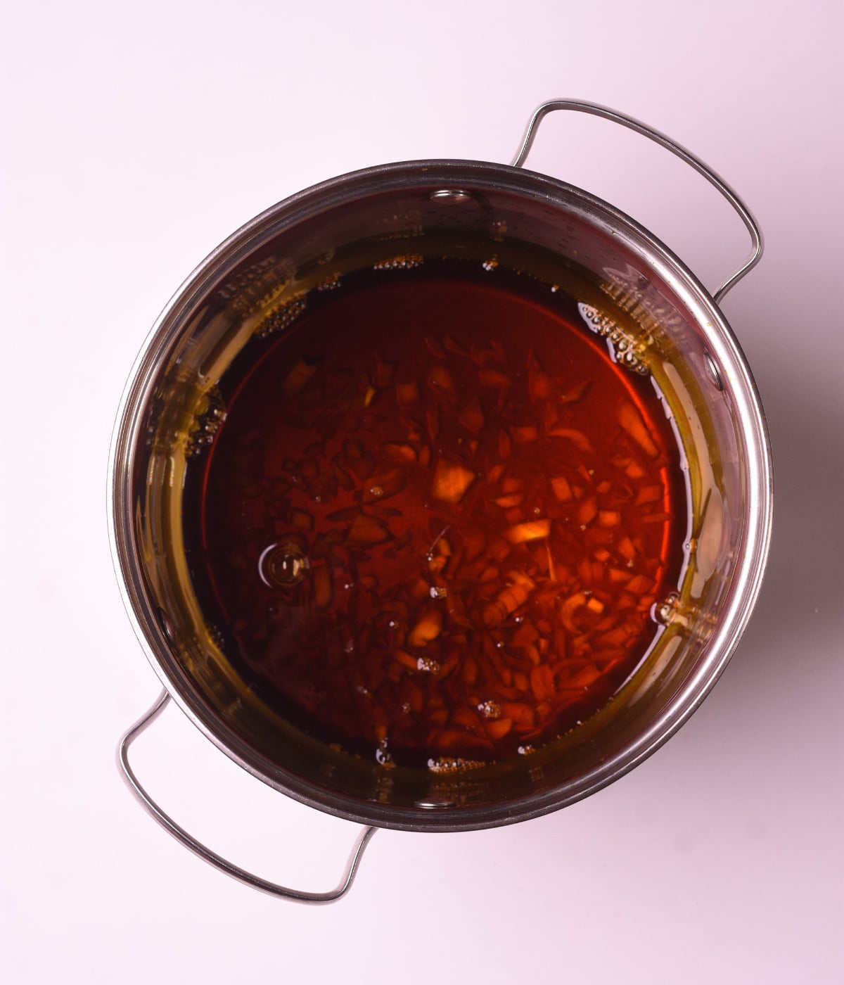 Palm oil and onion heated in a silver pot.