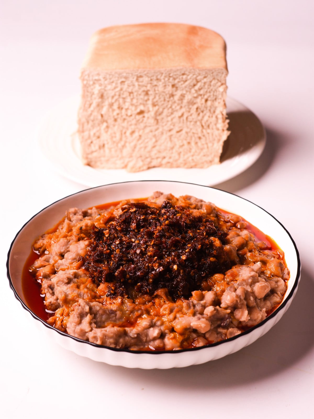 ewaagoyin in a white bowl with agege bread in the background.