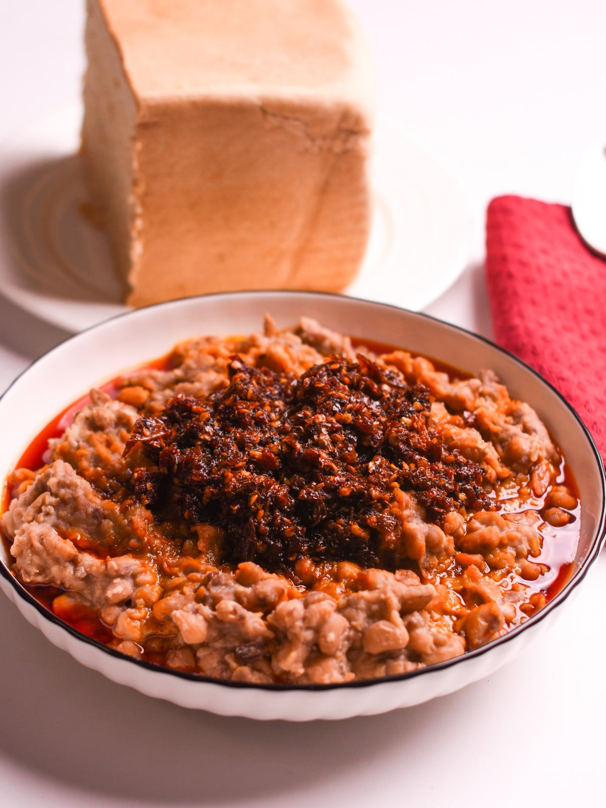 ewaagoyin in a white bowl with thick bread in the back.