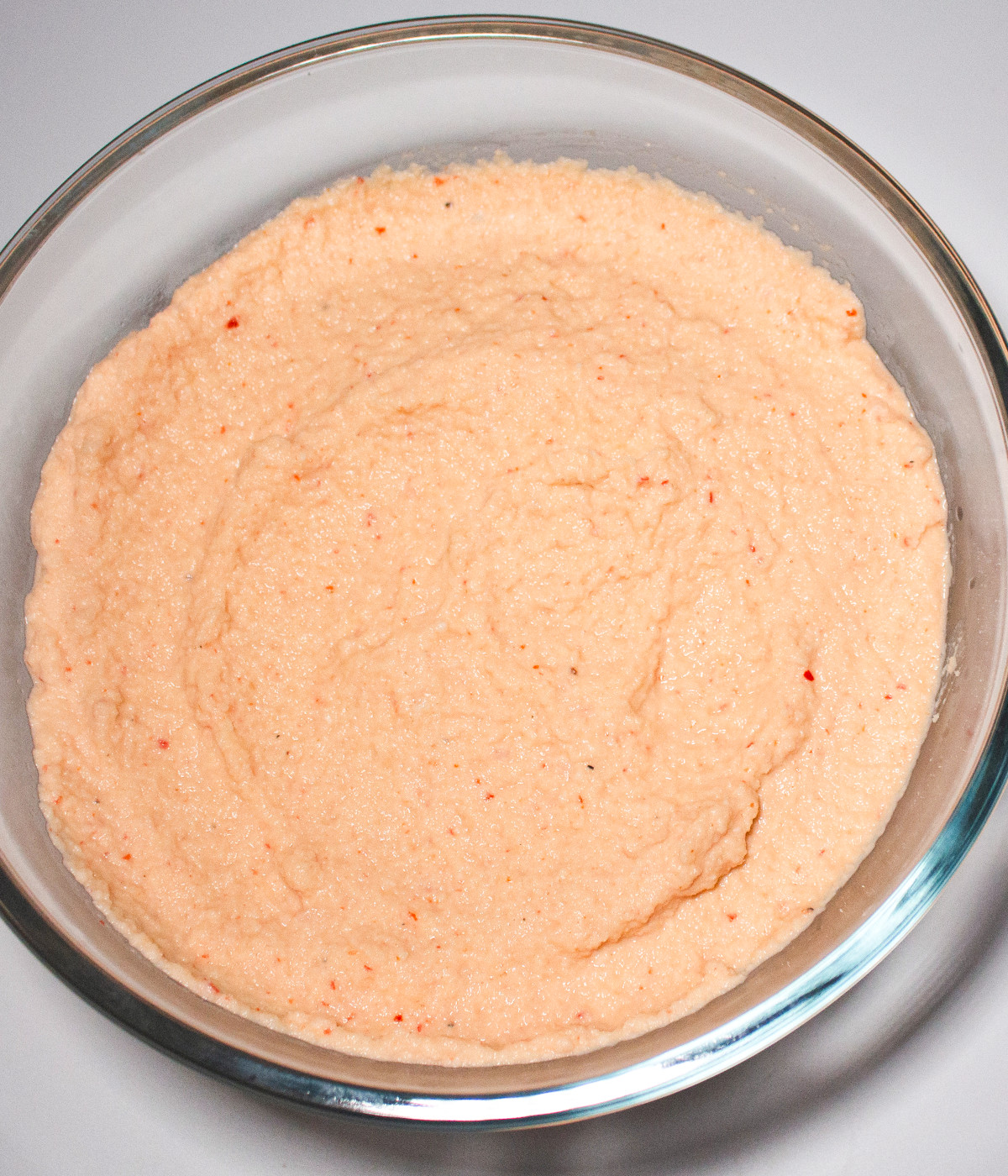 Blended peeled beans, onion, red bell pepper, scotch bonnets in a bowl.