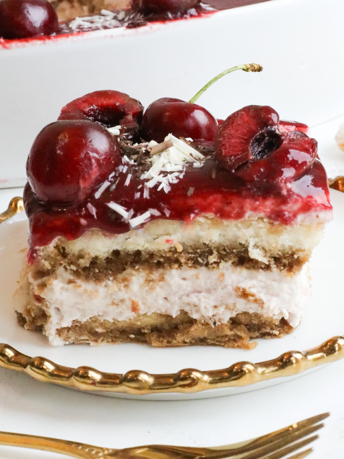A slice of cherries tiramisu on white and gold plate.
