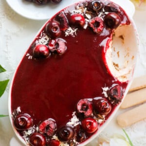 Cherries Tiramisu in a white oval dish with a slice taken.