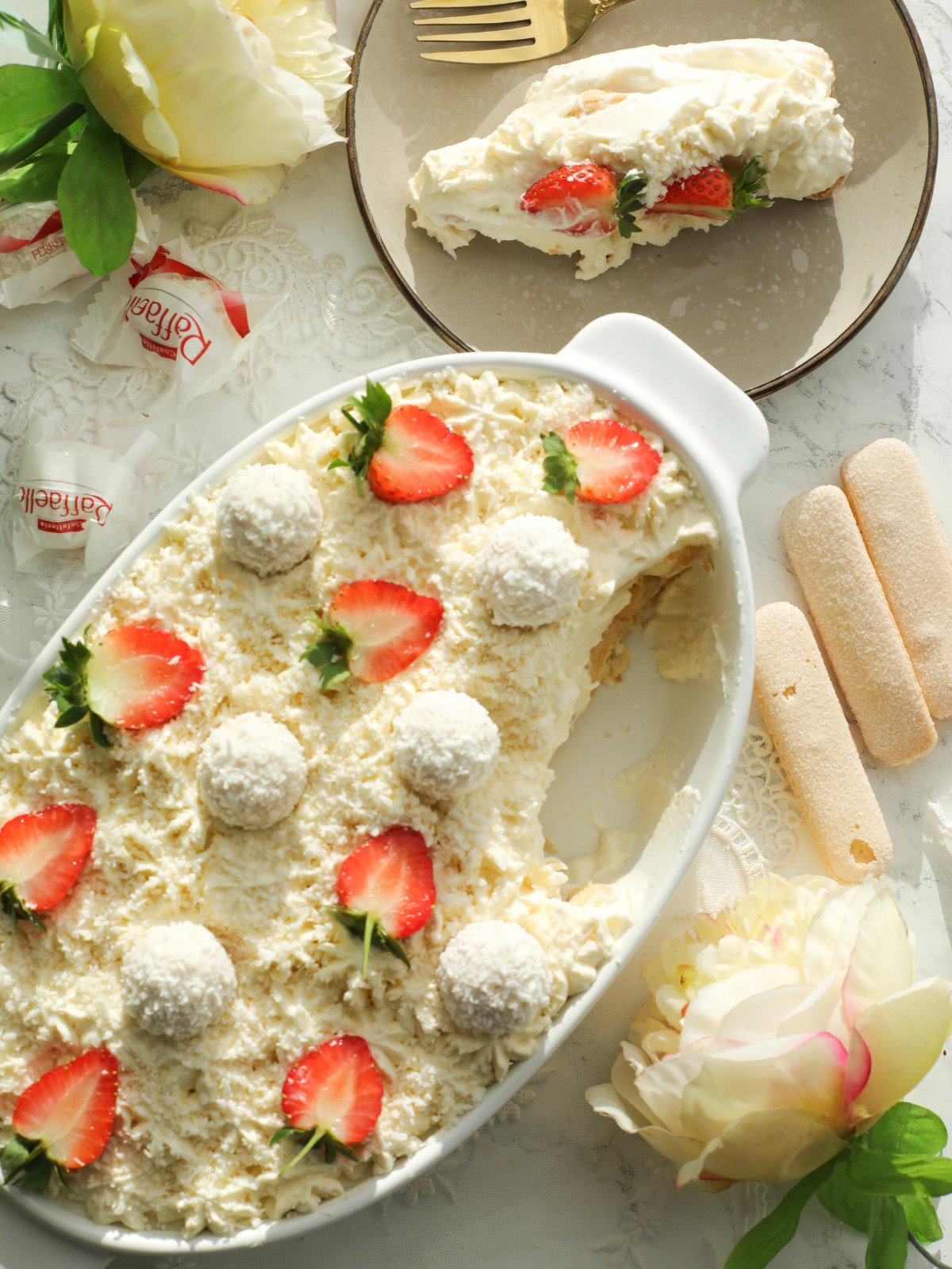Coconut Raffaellos Tiramisu in a white oval dish with a serving in a plate.