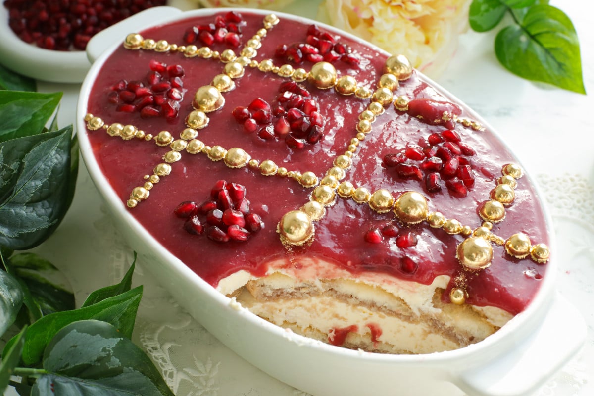 Pomegrante tiramisu in a white oval dish.