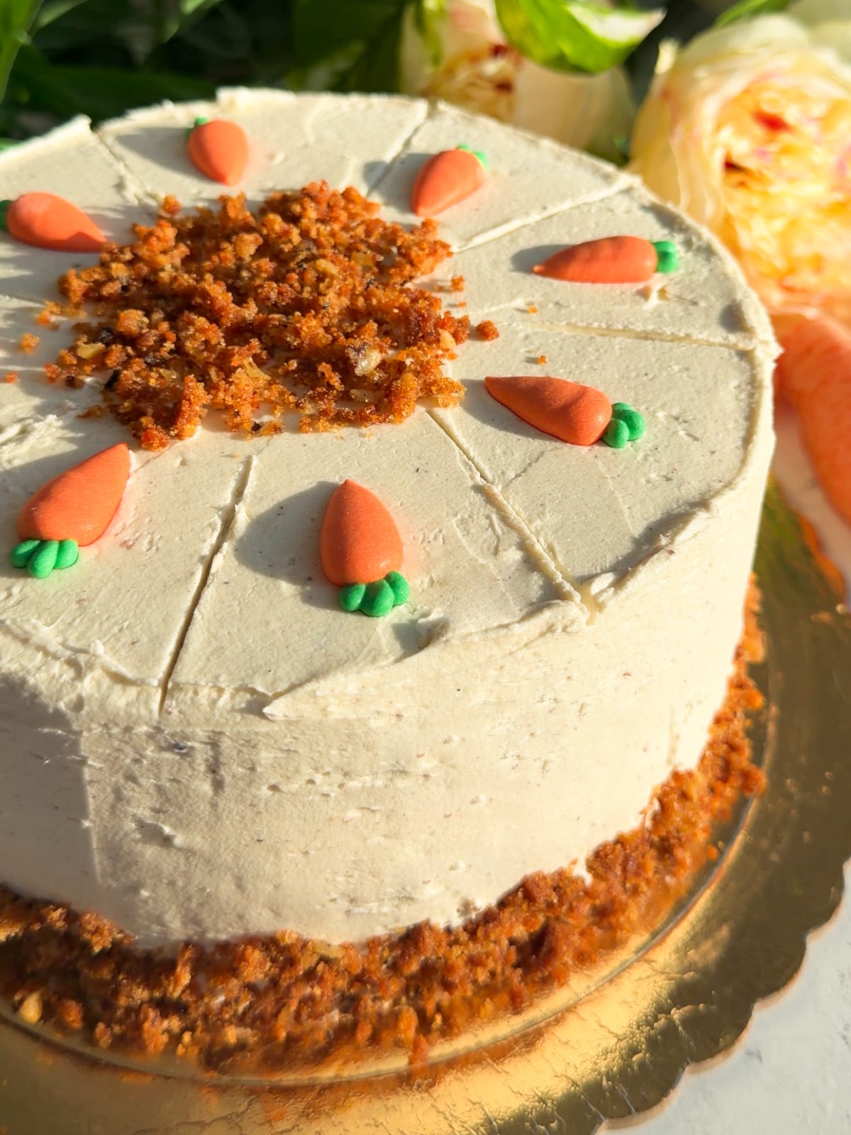 A whole carrot cheese cake cake on a gold board.