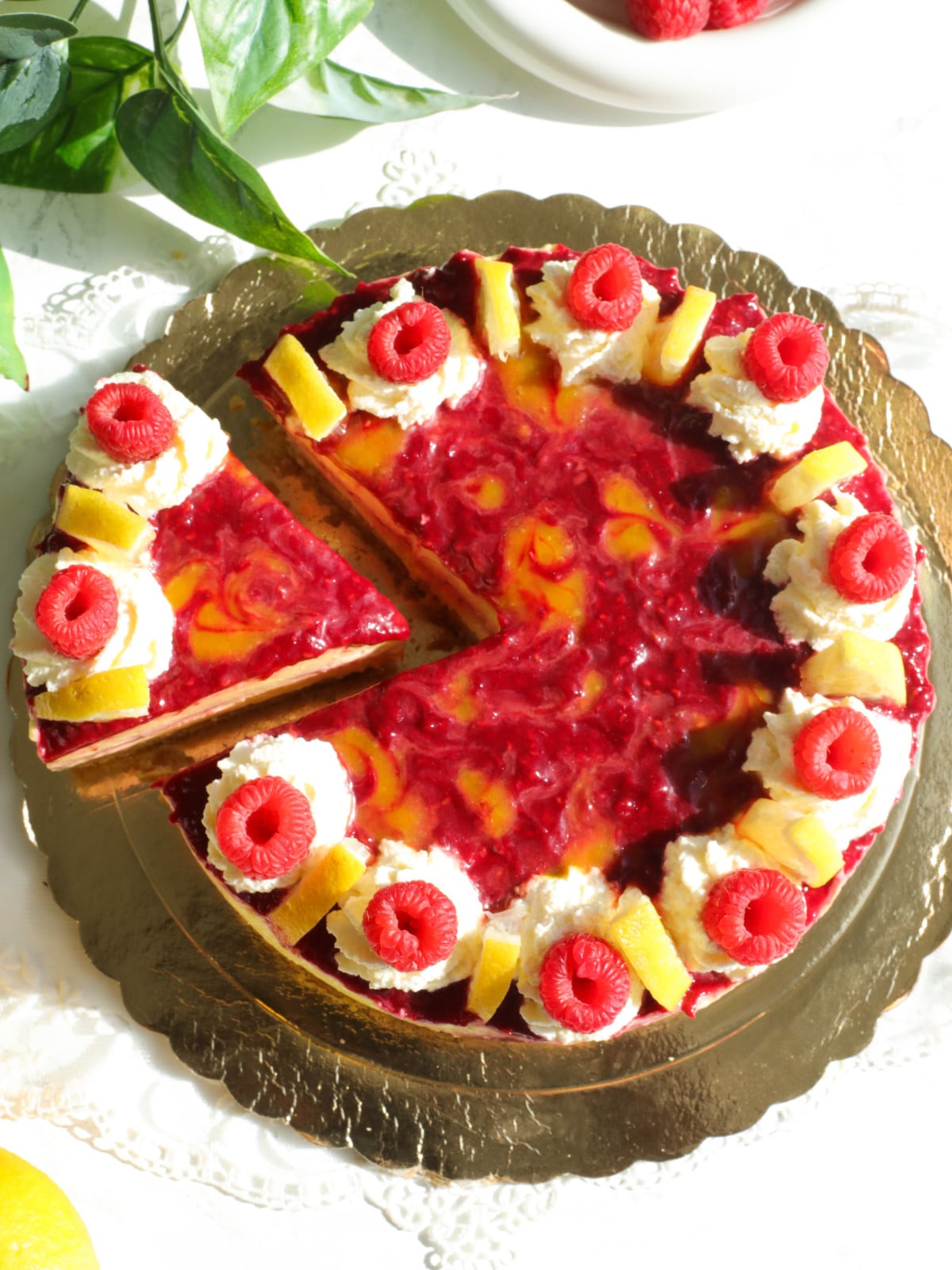 Lemon raspberry no bake cheesecake on a gold board.