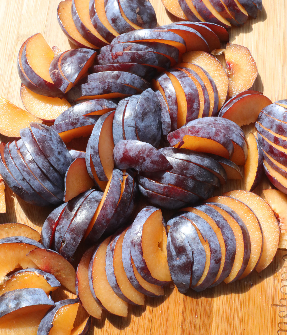 Slice plums on a wooden borad.