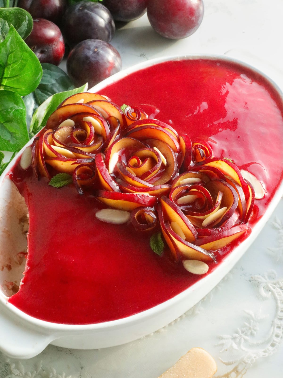 Plums tiramisu in a white dish with slices on top.
